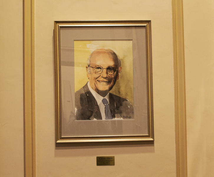 A watercolor portrait of Morris Cohen hangs on a wall