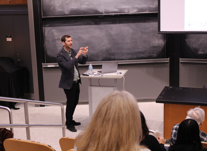 James LeBeau speaks in front of a blackboard as audience members listen