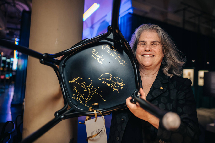Andrea Ghez shows off the bottom of a black chair with signatures in gold ink.
