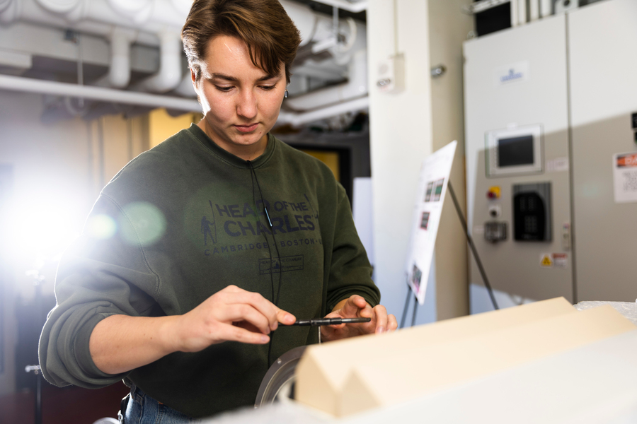Student Charlotte Gump works in lab with a bright light behind her.