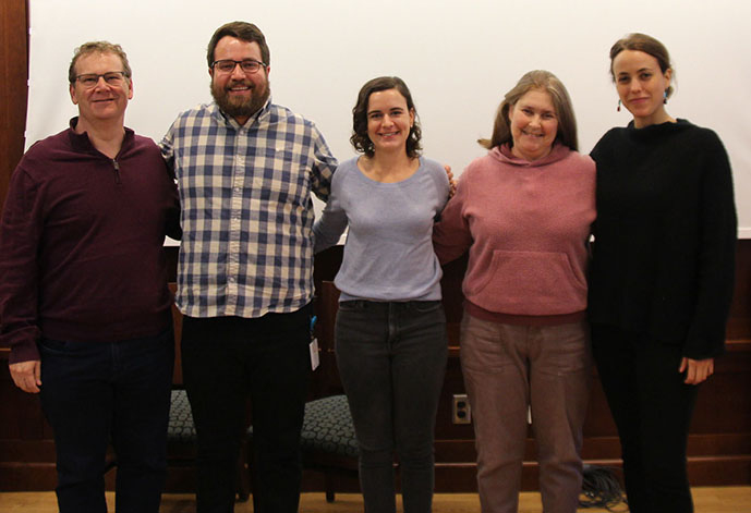 Photo of five people posing in a line with their arms around one another