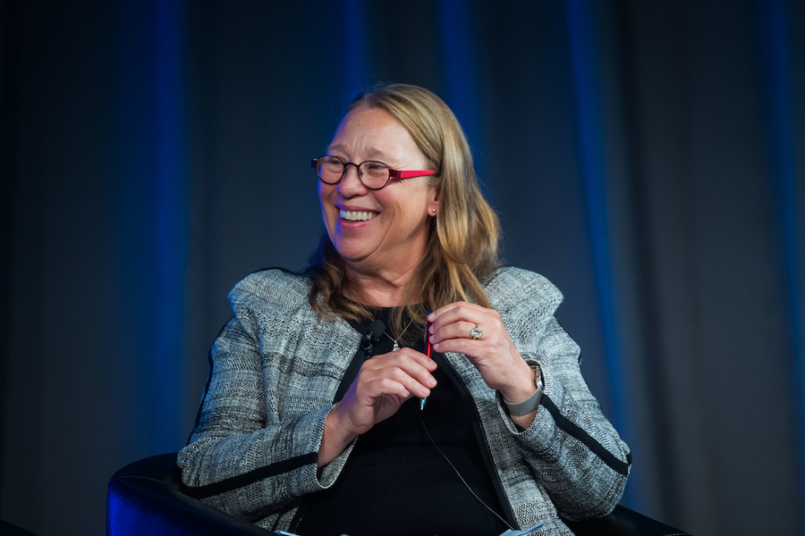Antje Danielson looks to her right while sitting in front of blue curtains.