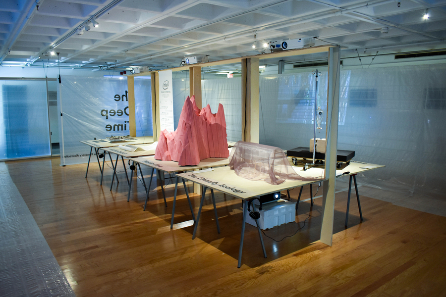 Gallery with four tables; a pink mountain-like sculpture sits in the middle