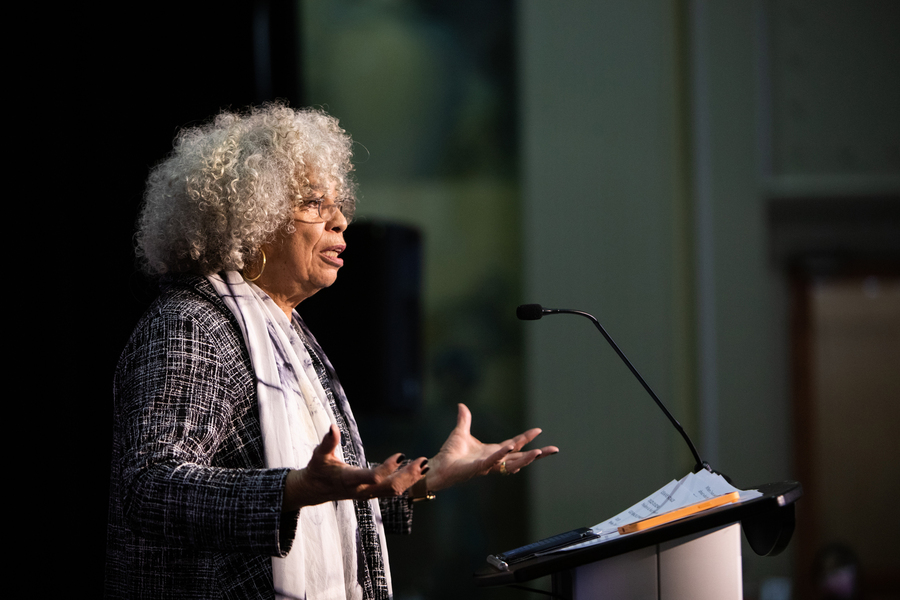 Side-view photo of Angela Davis speaking at a podium.