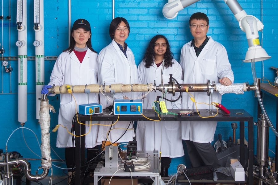 Chuwei Zhang, Sili Deng, Maanasa Bhat, and Jianan Zhang stand in white lab coats behind a metal cylinder wrapped in insulation and festooned with wires