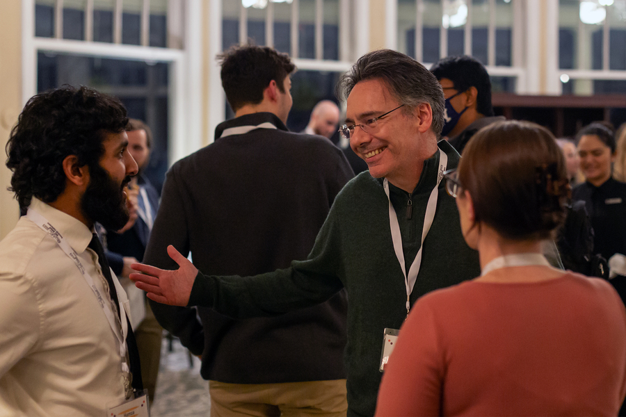 MIT professor William Oliver chats and smiles with other guests at a reception.