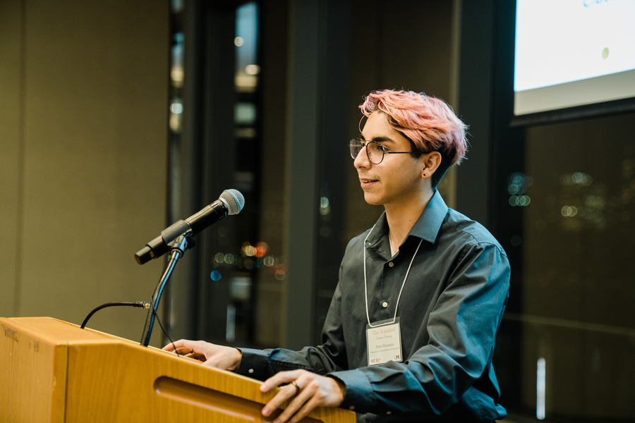 Photo of Alonso Hernandez standing at and resting his arms on a lecturn