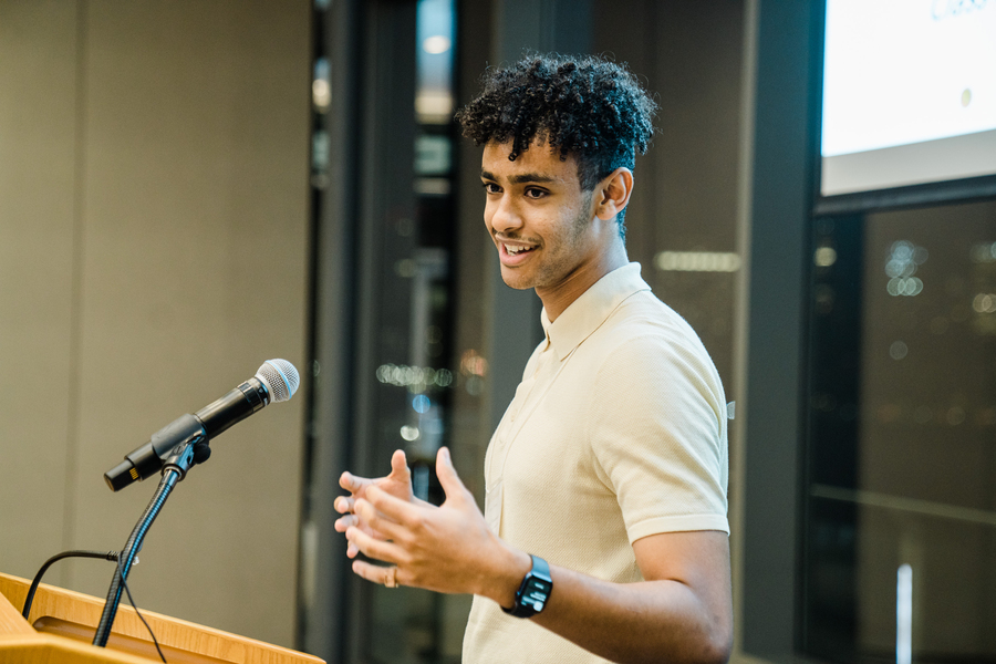 Side view of Bruke Wossenseged standing at a lecturn and gesturing with both hands