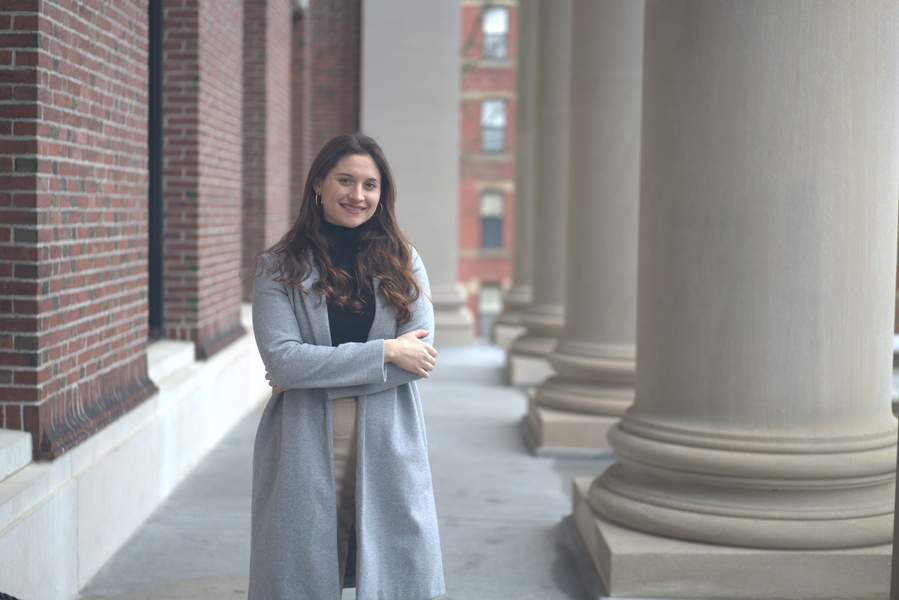 Juliana García-Mejía stands next to a brick buildings with large columns.