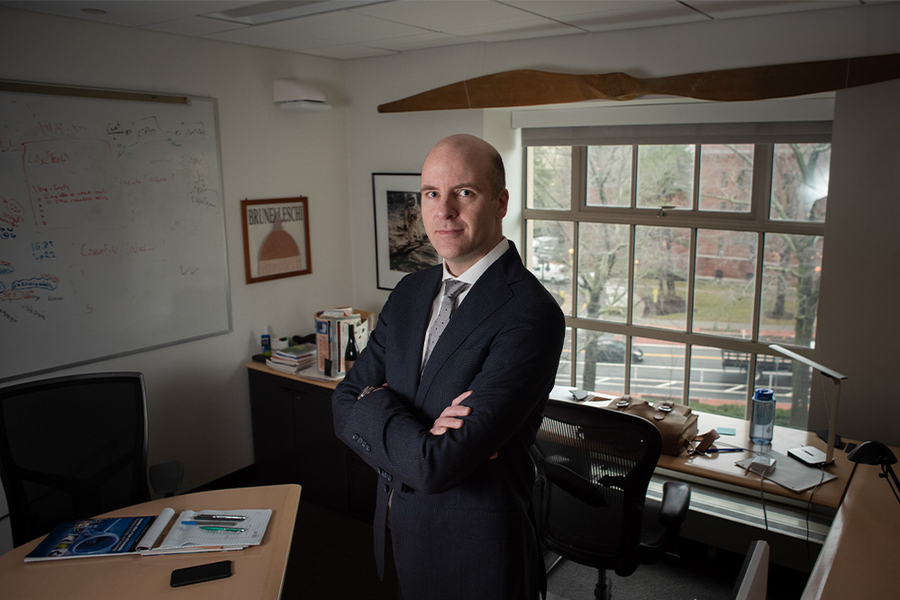 Portrait photo of Bruce Cameron standing in a small office with windows in the background