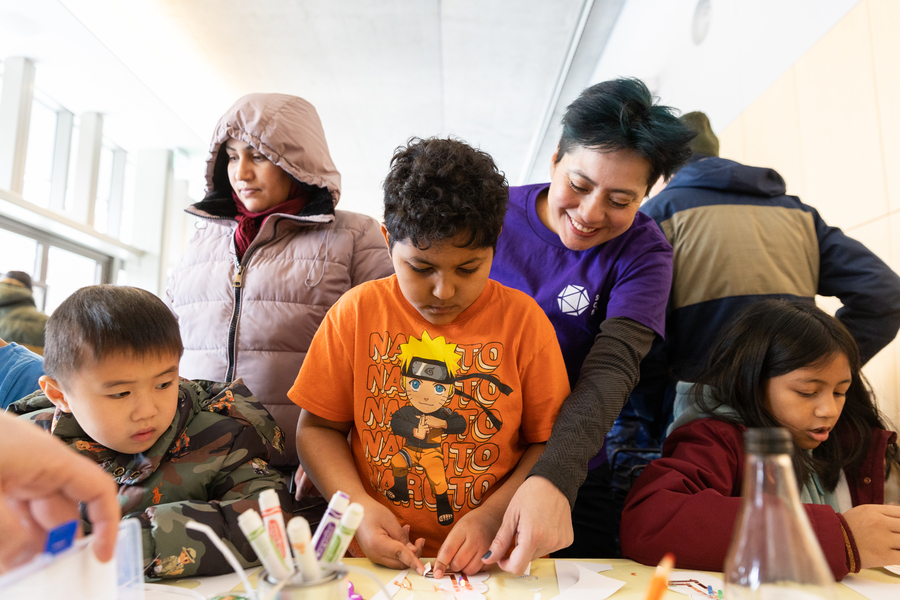 Three children doing a hands-on activity on a table with an adult helping