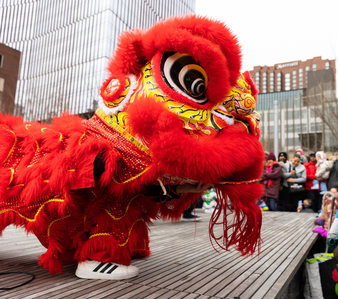 Performer in bright red Chinese-style lion costume on outdoor stage