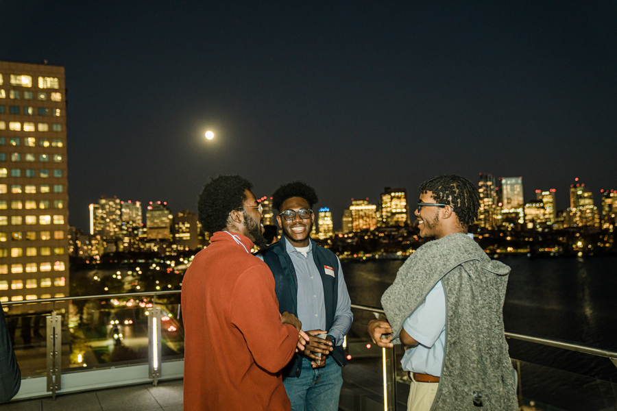 Photo of three students mingling by moonlight on the Samberg Center rooftop