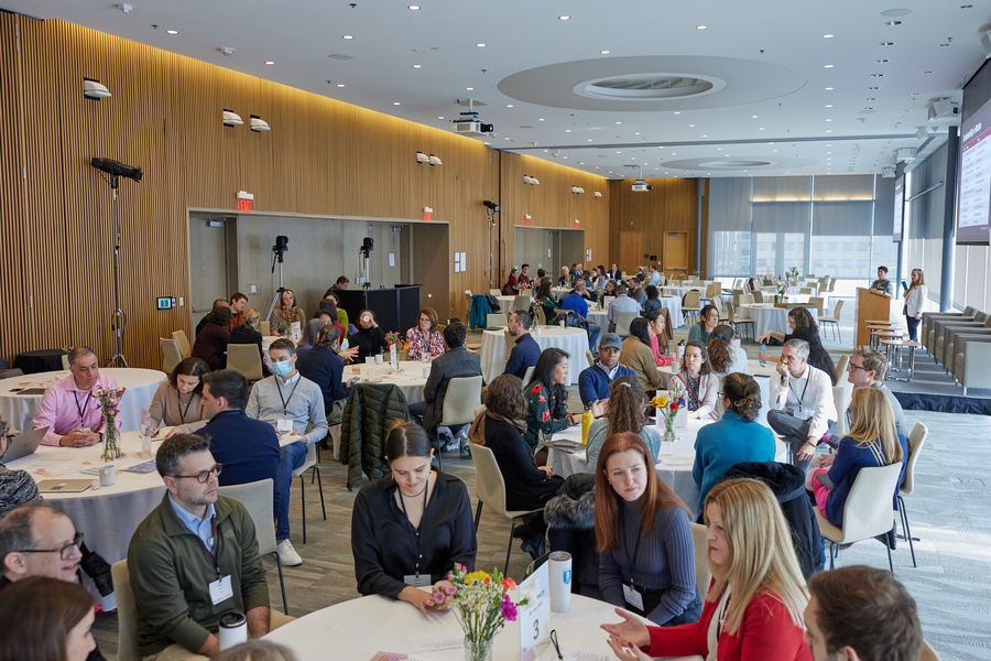 Scores of people sit at round tables in a function room