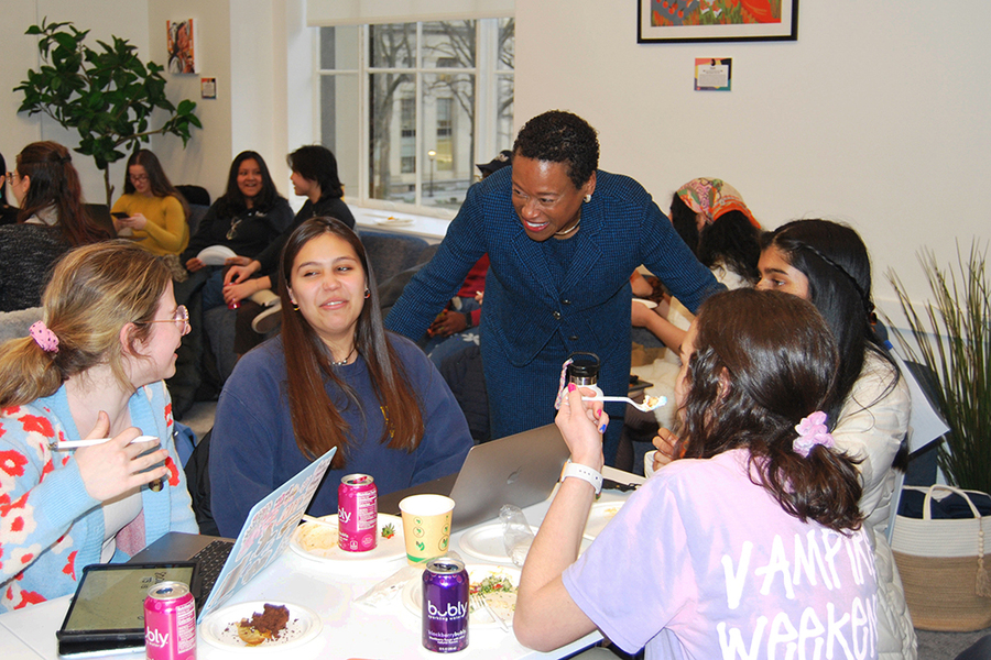 Melissa Nobles chats with a group of students sitting at a table
