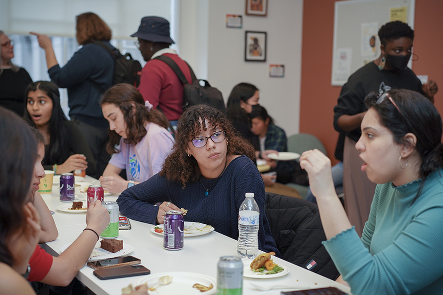 About a dozen women sit around a table and mingle around the Margaret Cheney Room