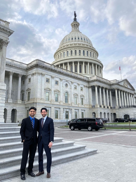 Two MIT students in suits pose in front of the US Capitol Building