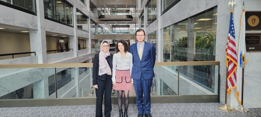 Three people stand on a catwalk over an atrium in an office building
