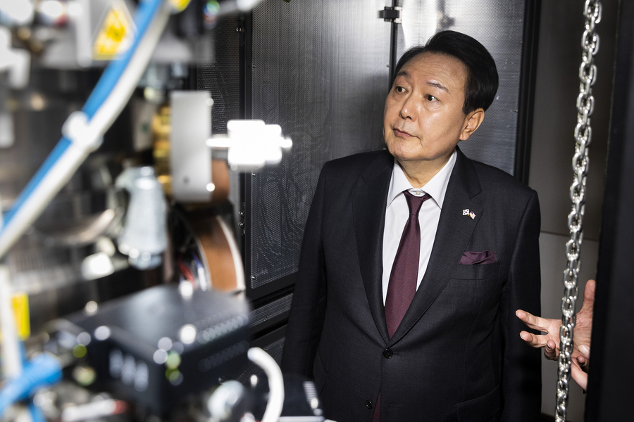 President Yoon Suk Yeol looks at a large device, which is out-of-focus in the foreground.