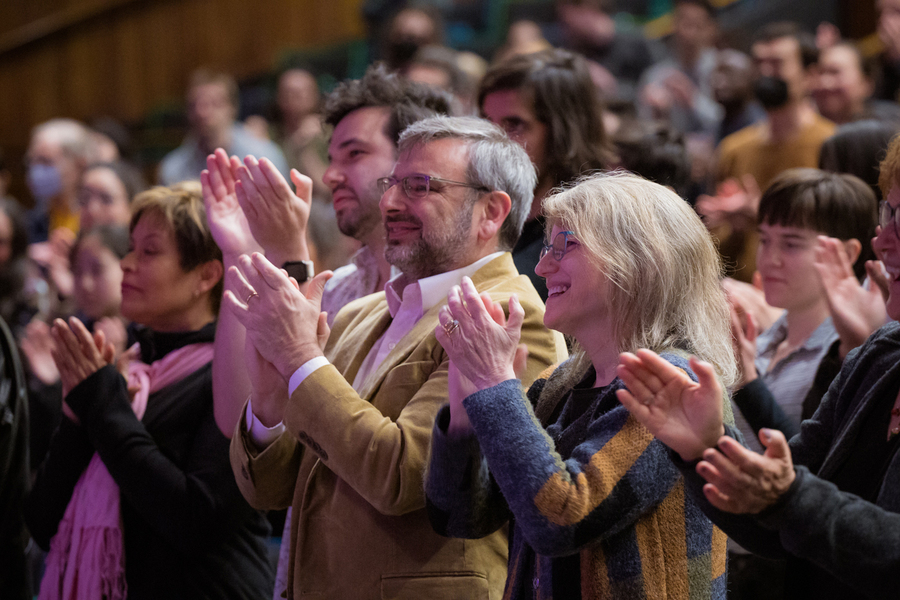 Sally Kornbluth and other audience members stand and applaud.