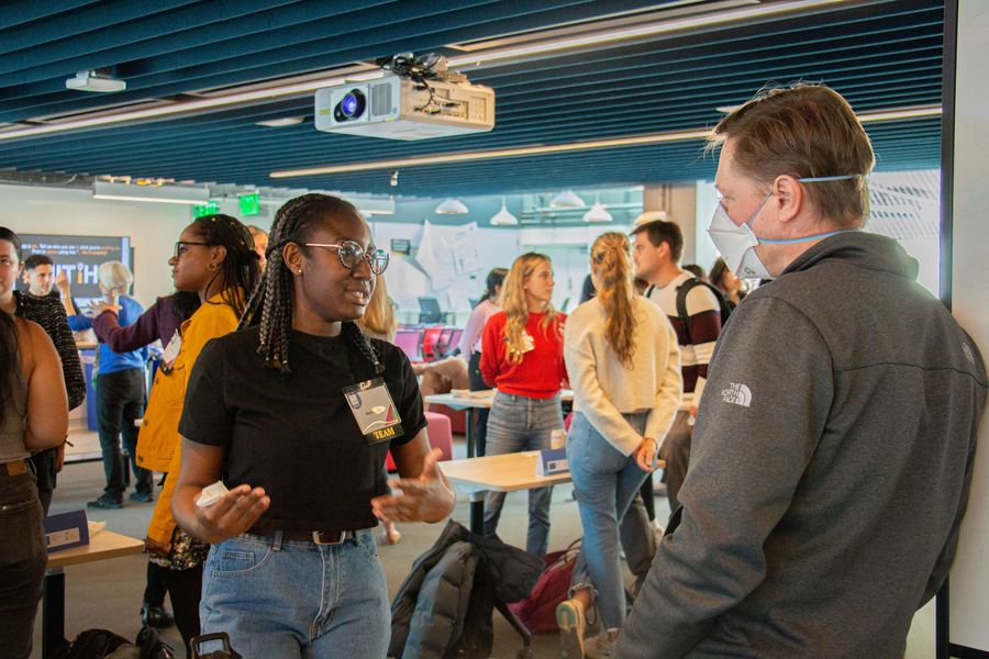 More than a dozen members of the IDEAS community mingling and speaking to one another in a room.