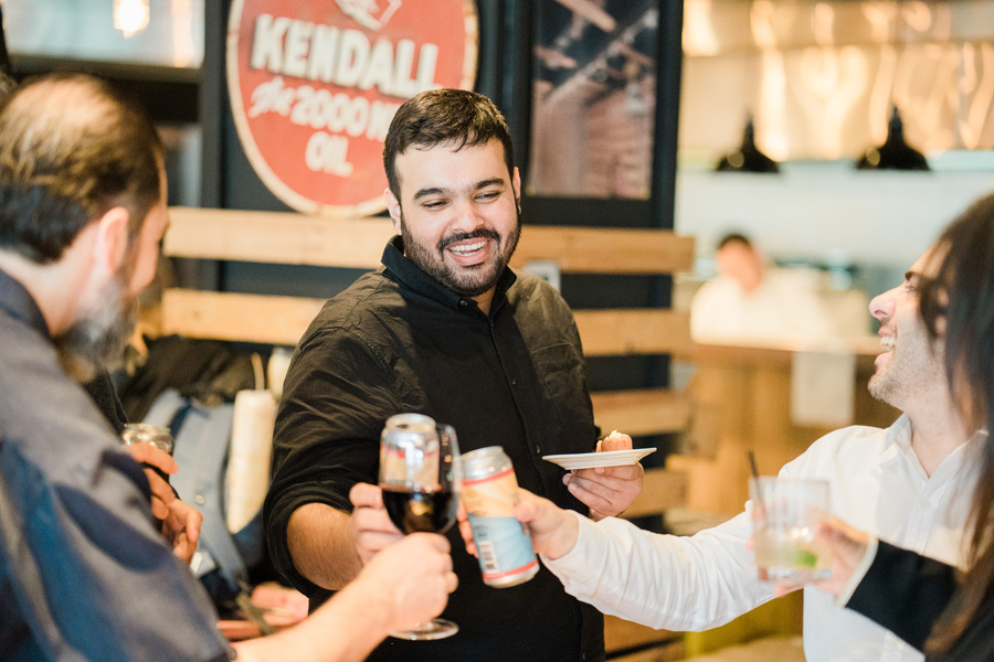 Photo of four people toasting beverages together and cheering.