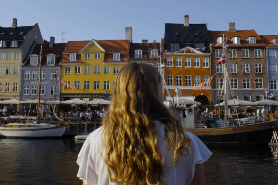 With her back to the camera, Meredith Arterburn looks out a harbor with a row of buildings in the background.