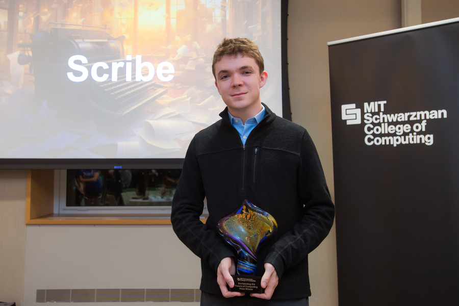 A student in a black sweater poses with an award next to a MIT Schwarzman College of Computing banner.