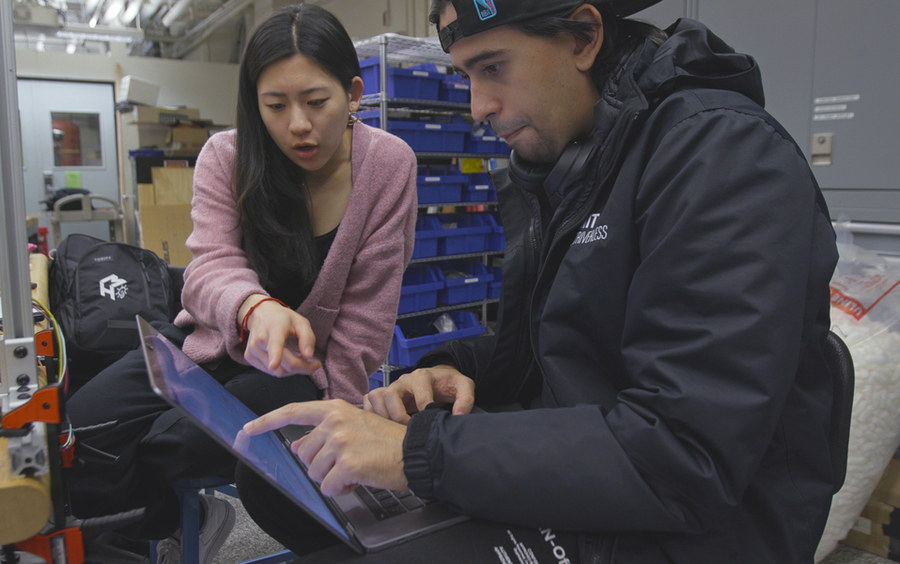2 students point at a laptop screen as they collaborate in a lab.