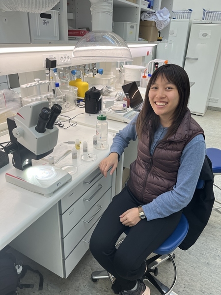Andrea Lo seated at a lab bench and smiling at the camera