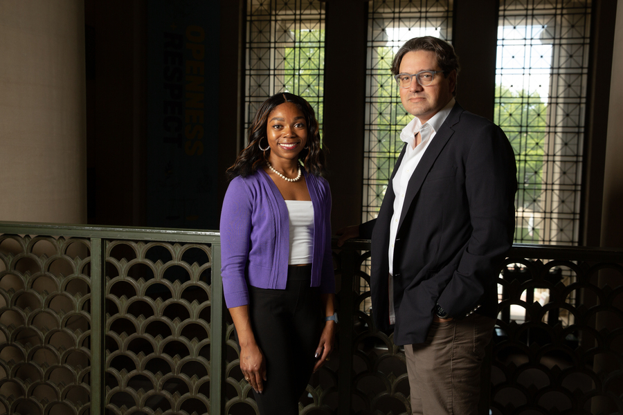 Crystan McLymore and Giovanni Traverso stand side by side on a balcony at MIT with windows in the background