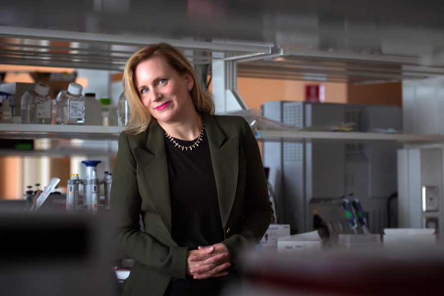 Angela Koehler stands in lab with shelves and equipment in the background