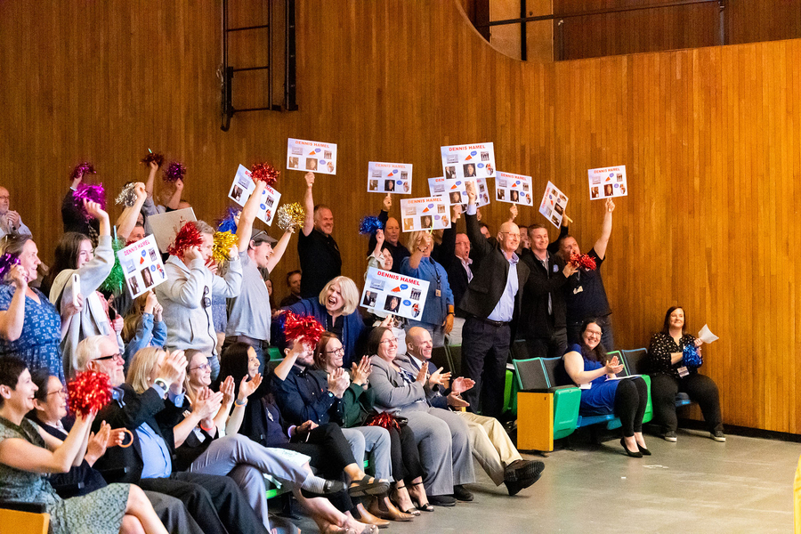 30-40 adults in an auditorium laugh, clap, hold signs, and wave pompoms at the MIT Excellence Awards + Collier Medal event