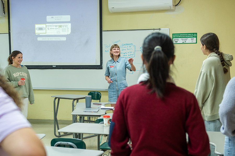 Taylor Baum speaks in front of a classroom while several students stand around her