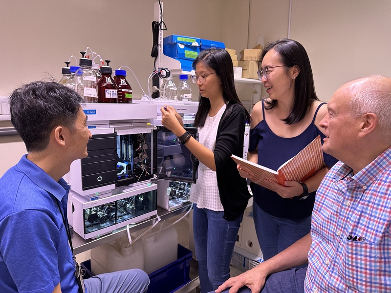 Four researchers surround a mass spectrometer