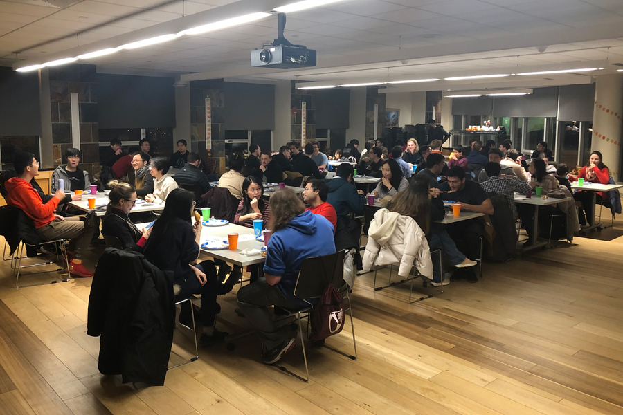 Many people eat at tables in a large room.