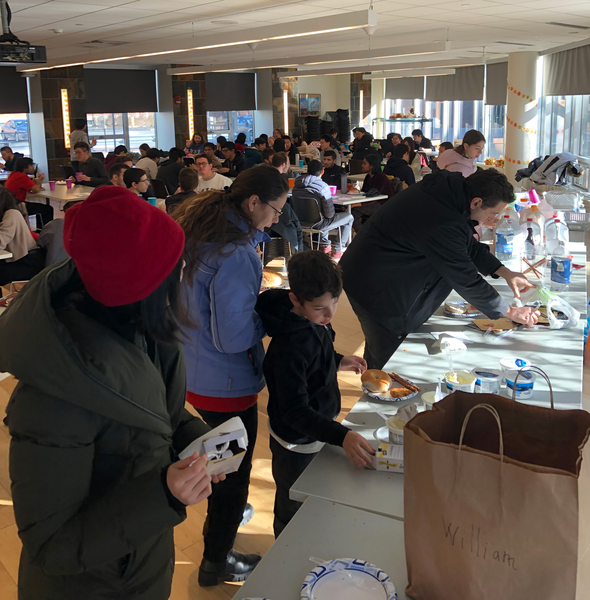 People wait in line for food at a popular event indoors.