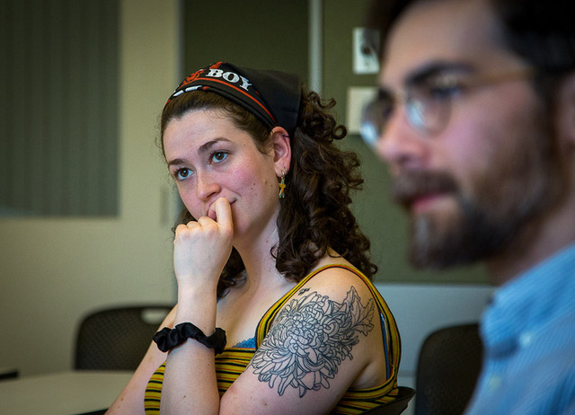 Closeup of Anna Bair sitting in a classroom listening to a conversation. Justin Khoo is seen in the foreground to her right.