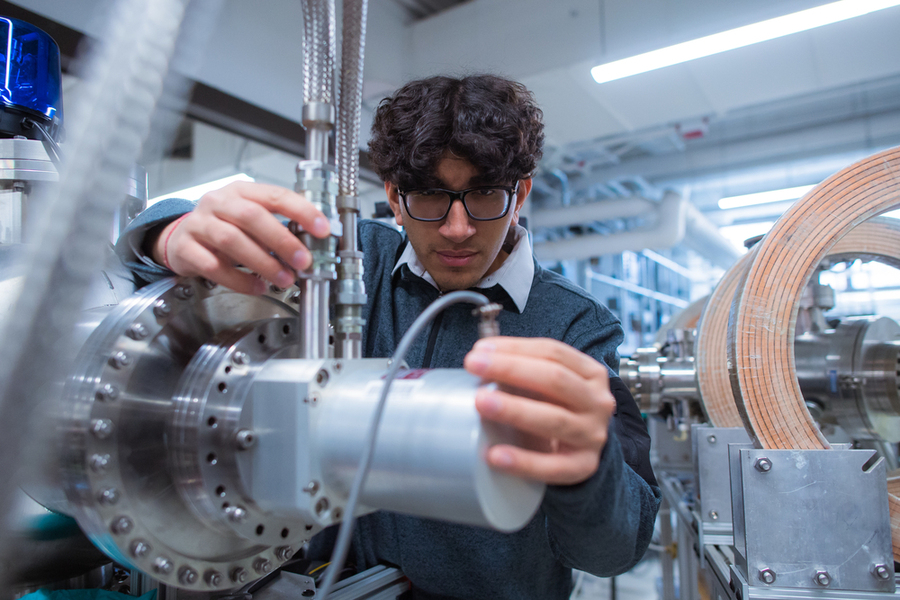 Akarsh Aurora looking at a large, heavy-duty piece of lab equipment