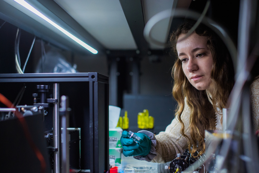 Lauryn Kortman leaning over lab equipment while holding a sample.