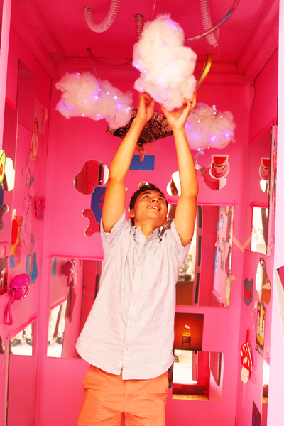 A student reaches overhead to touch a small fluff cloud hanging inside Barbis