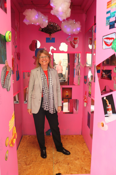 President Kornbluth smiling inside a pink polystyrene phone-booth-sized box festooned with whimsical decorations
