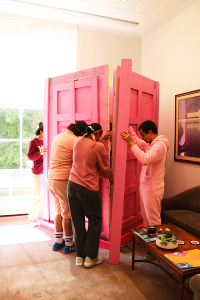 Four students hold up the pink polystyrene walls of Barbis as they attach them
