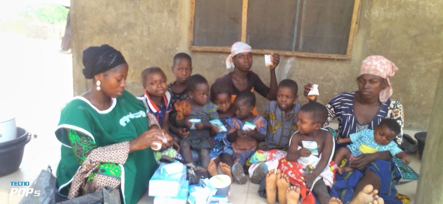 Photo of a dozen individuals, mostly children plus three women, sitting in a group.
