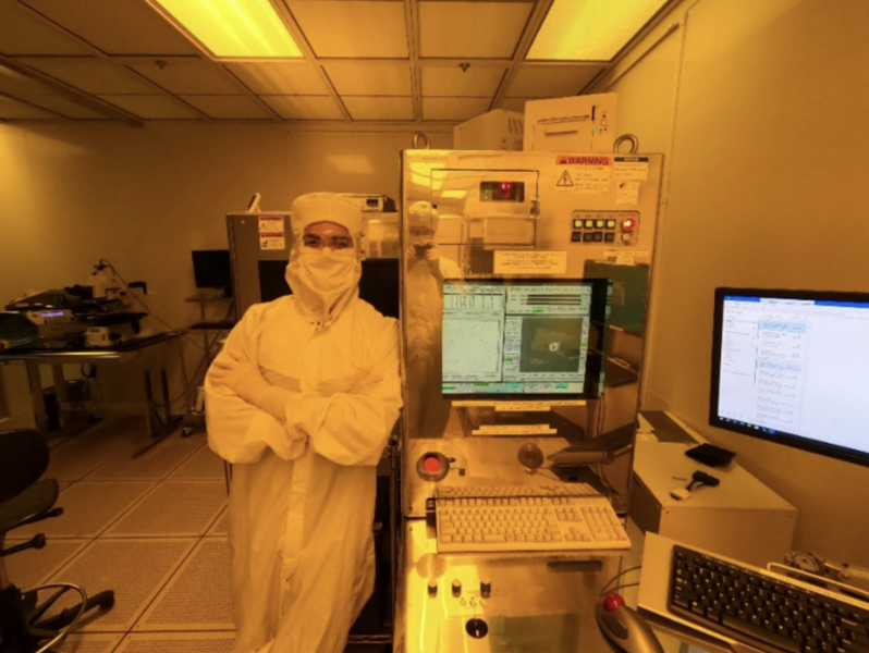 Daniel Reyes, wearing a white cleansuit, poses for a photo in the Microelectronics Laboratory.