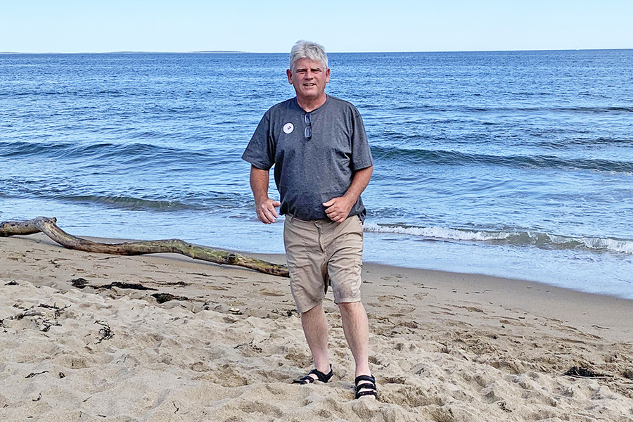 Photo of Steven Goldman standing on a beach with clear water and clear skies behind him