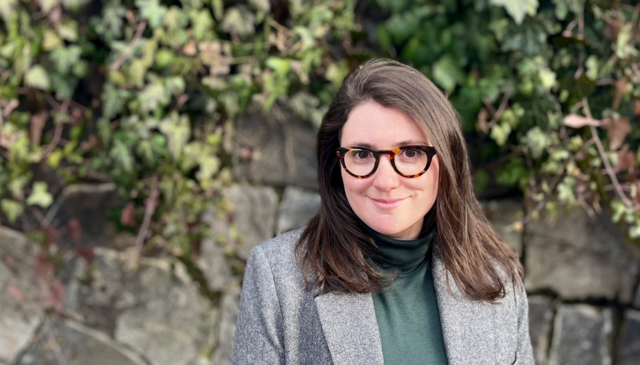 Portrait of Chloe Wittenberg standing in front of a stone wall with ivy creeping down the side