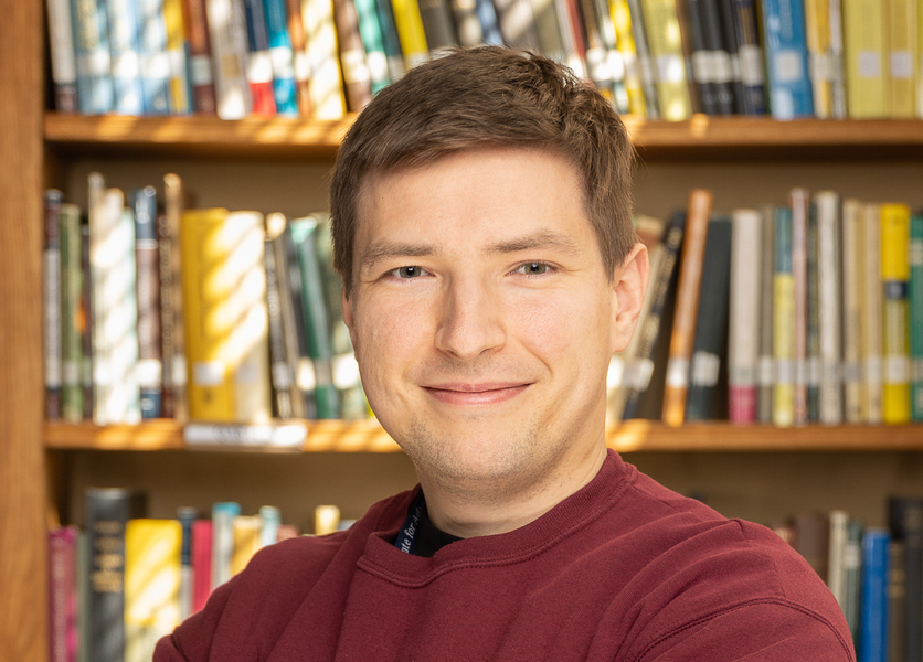 Headhshot of Mikhail Ivanov with a bookcase behind him