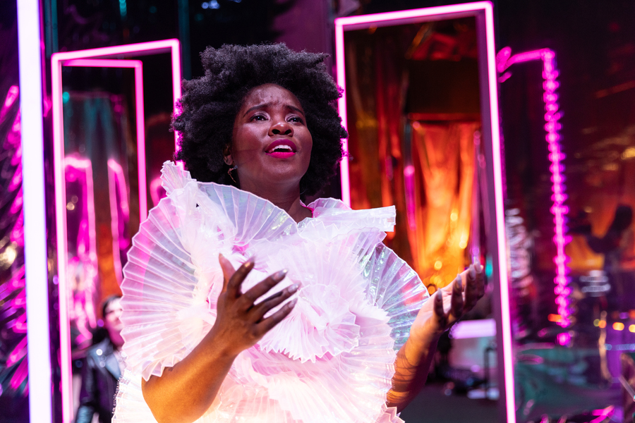 Kristin Young in white costume on a theater set with pink lights