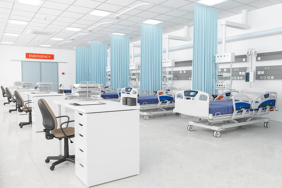 An empty emergency room with four sets of hospital beds and reception desks.